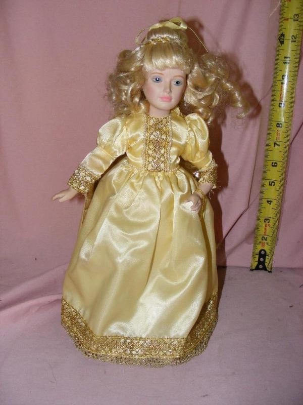 lot 57 image: Doll on stand, yellow gold dress...