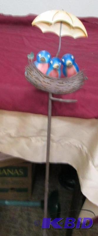 Three birds in a nest with an umbrella over t...