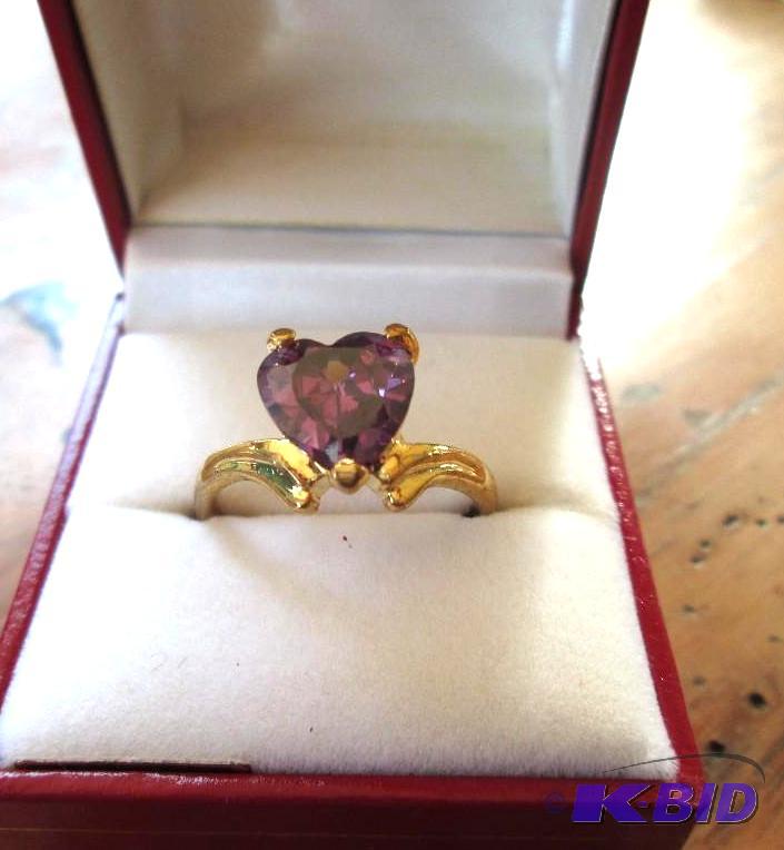 lot 285 image: Gold colored band ring with purple stone hear...