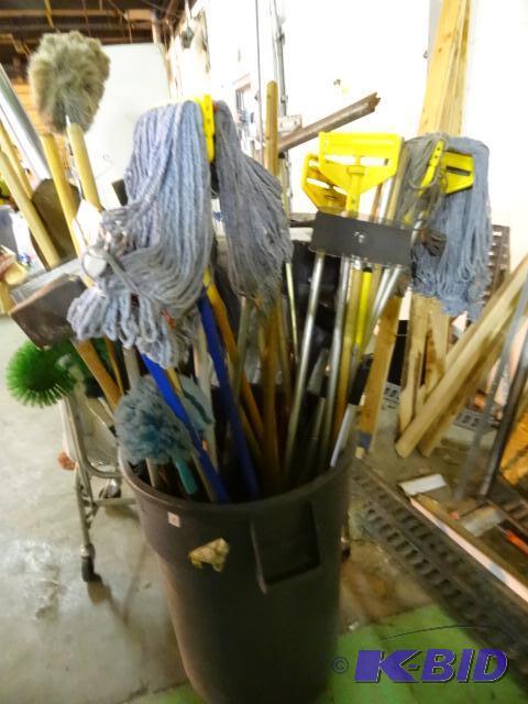 lot 53 image: Brute 55 gal garbage can with mops, brooms, s...