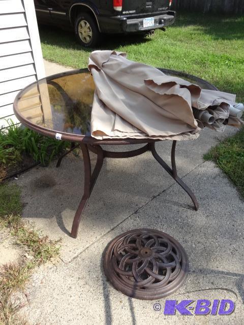 lot 107 image: Metal patio table with glass top. Umbrella an...
