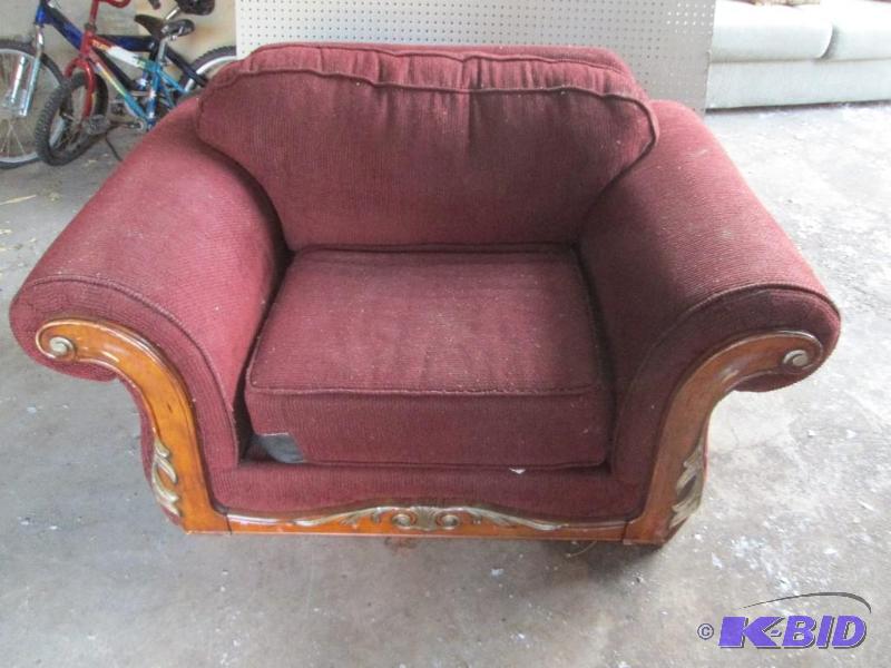 Red upholstered chair with wood frame, rip in...