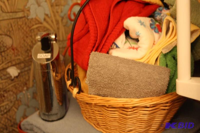 lot 70 image: Shelf Lot Including Ornate Orange Metal Wire Shelf, Wicker Baskets wLids, Bath Towels, And More.