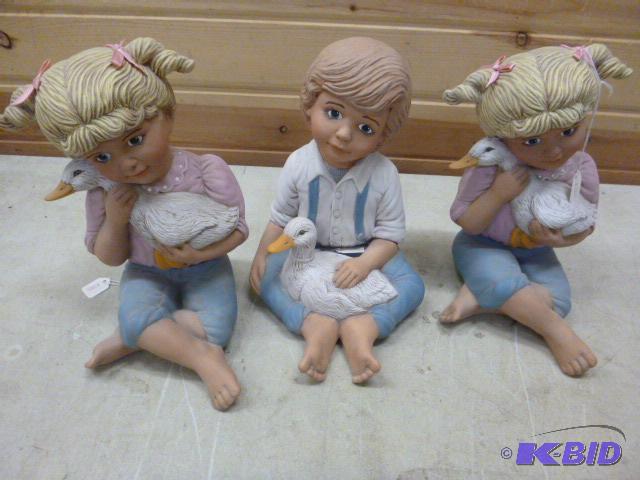 lot 90 image: Three Figurines Two girls and a boy each hold...