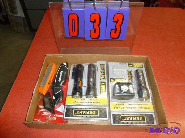 Flat of flashlights and utility knives. As sh...